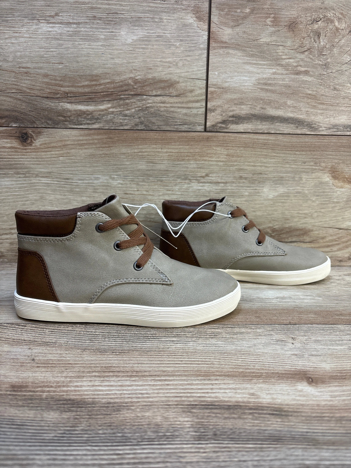 Kids' taupe and brown high top sneakers with white soles on wood background