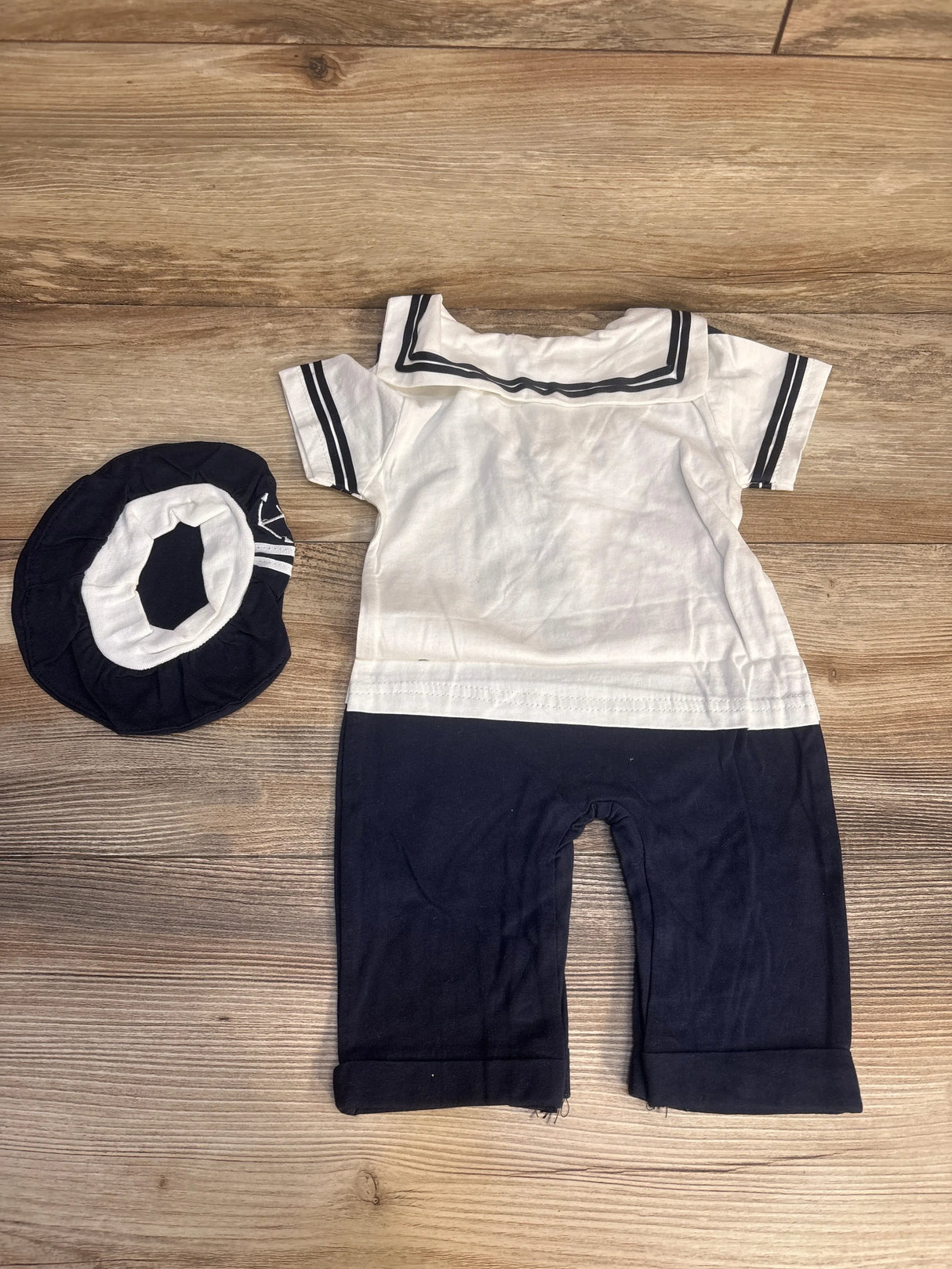Baby navy and white sailor romper with matching hat on wooden background