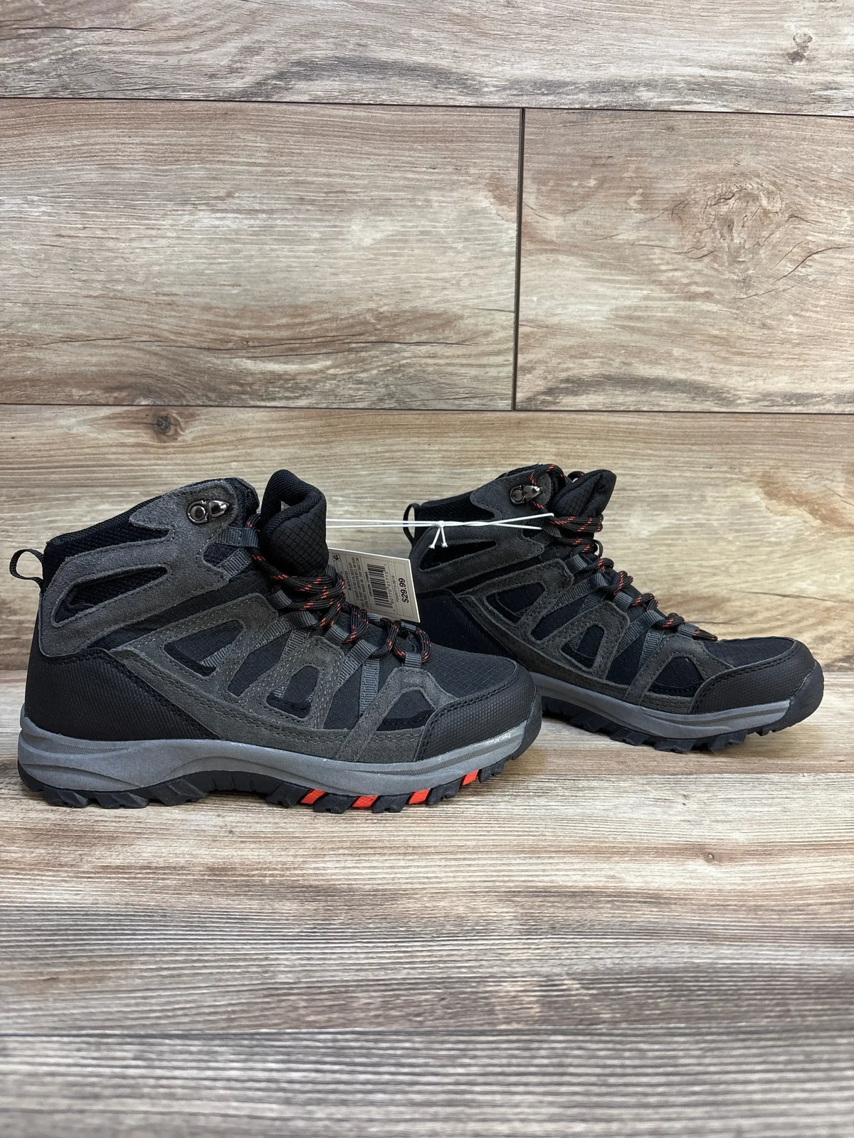 Pair of black and gray children’s hiking boots with red accents on wooden background