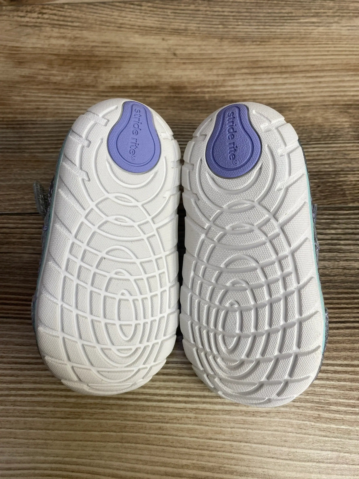 Pair of toddler Stride Rite shoes with white textured soles on wood background