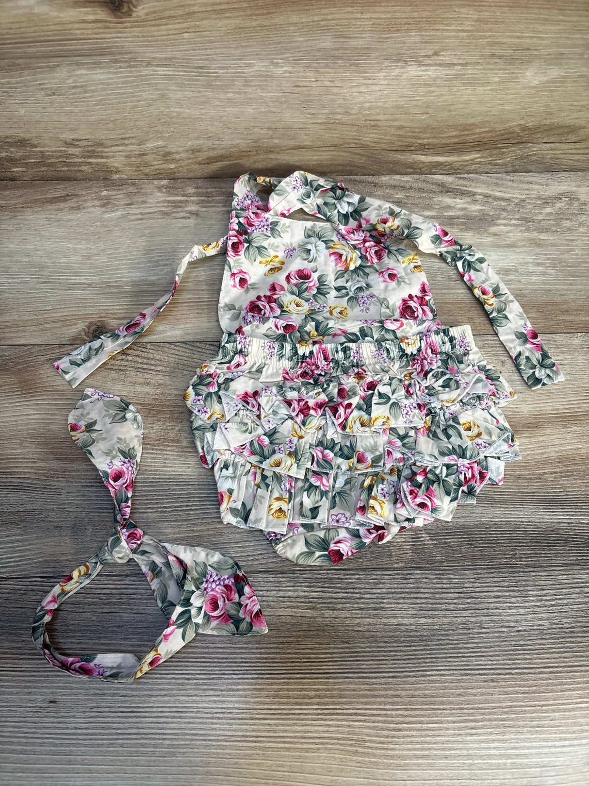 Floral ruffled baby romper and matching headband on wood background