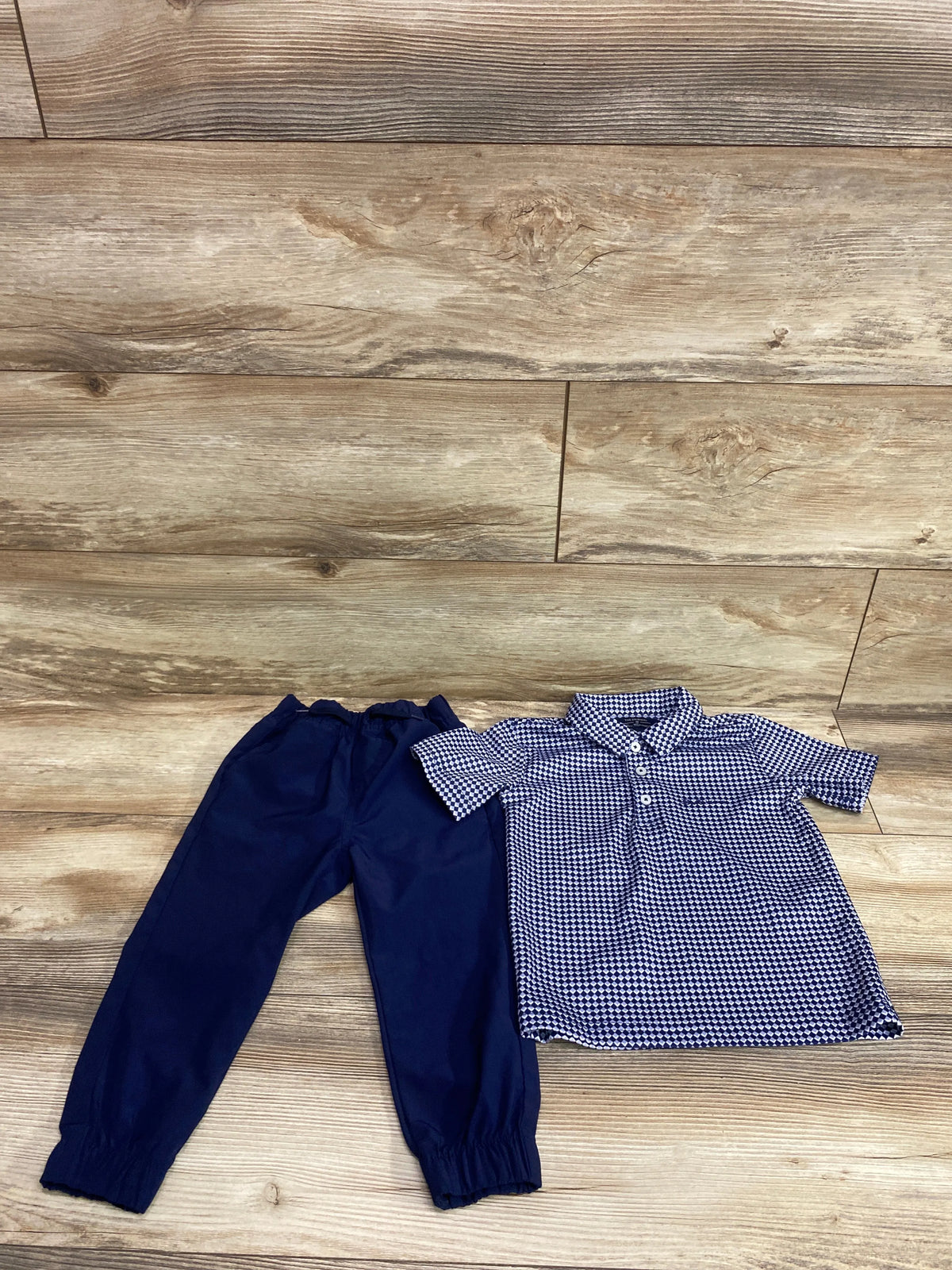 Overhead view of Ben Sherman 2pc Tech Polo and Pant Set showcasing a patterned collared polo and solid navy pants on wood flooring