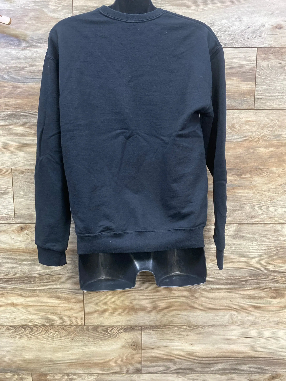 Black long-sleeve sweatshirt displayed on mannequin against wood flooring