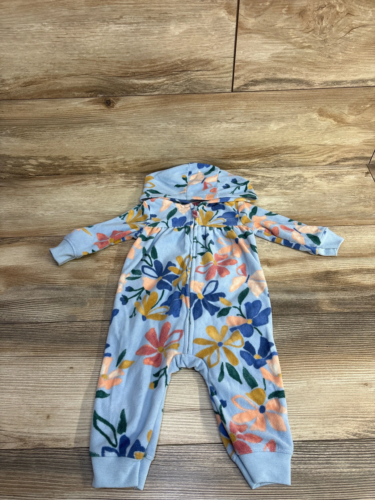 Baby fleece onesie with hood and colorful floral pattern on wooden floor