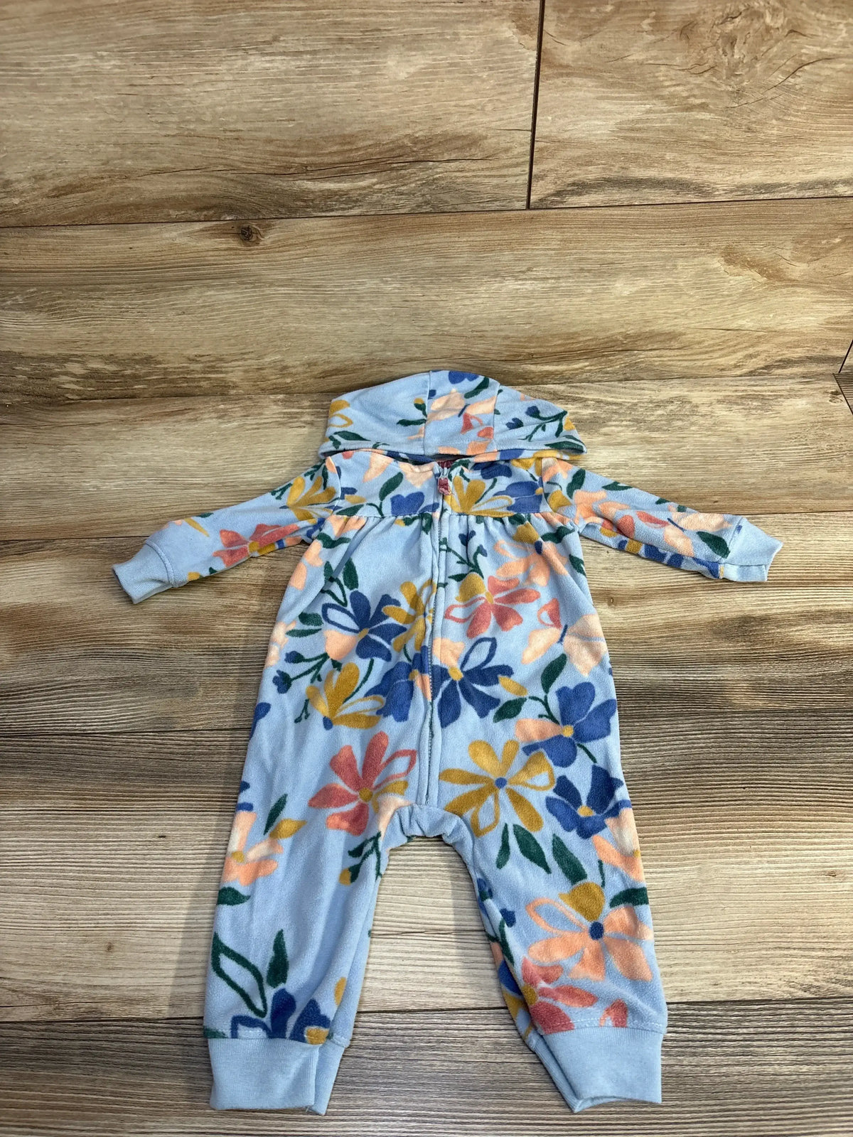 Baby fleece onesie with hood and colorful floral pattern on wooden floor