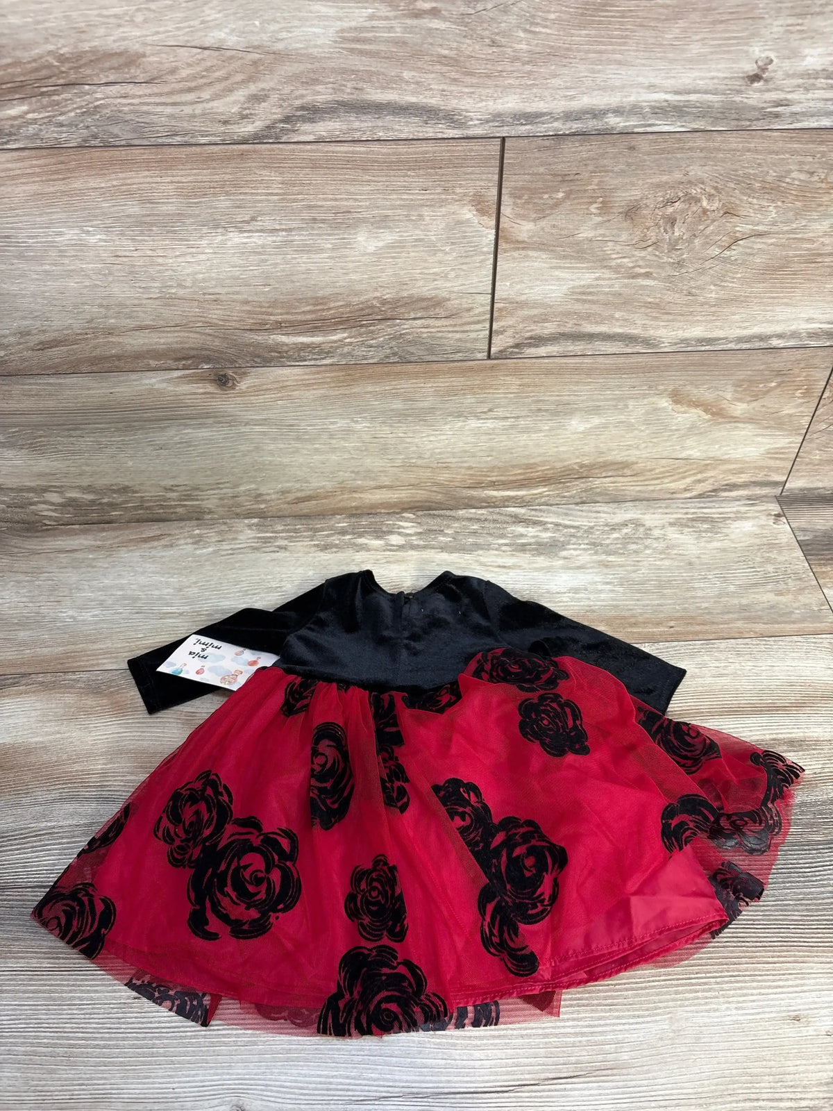 Black and red toddler dress with rose patterns on wooden floor
