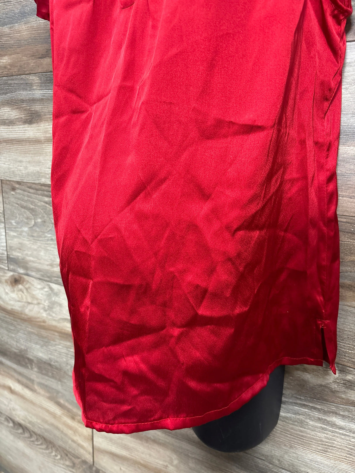 Red satin kids dress close-up on wood background, gently used children's clothing