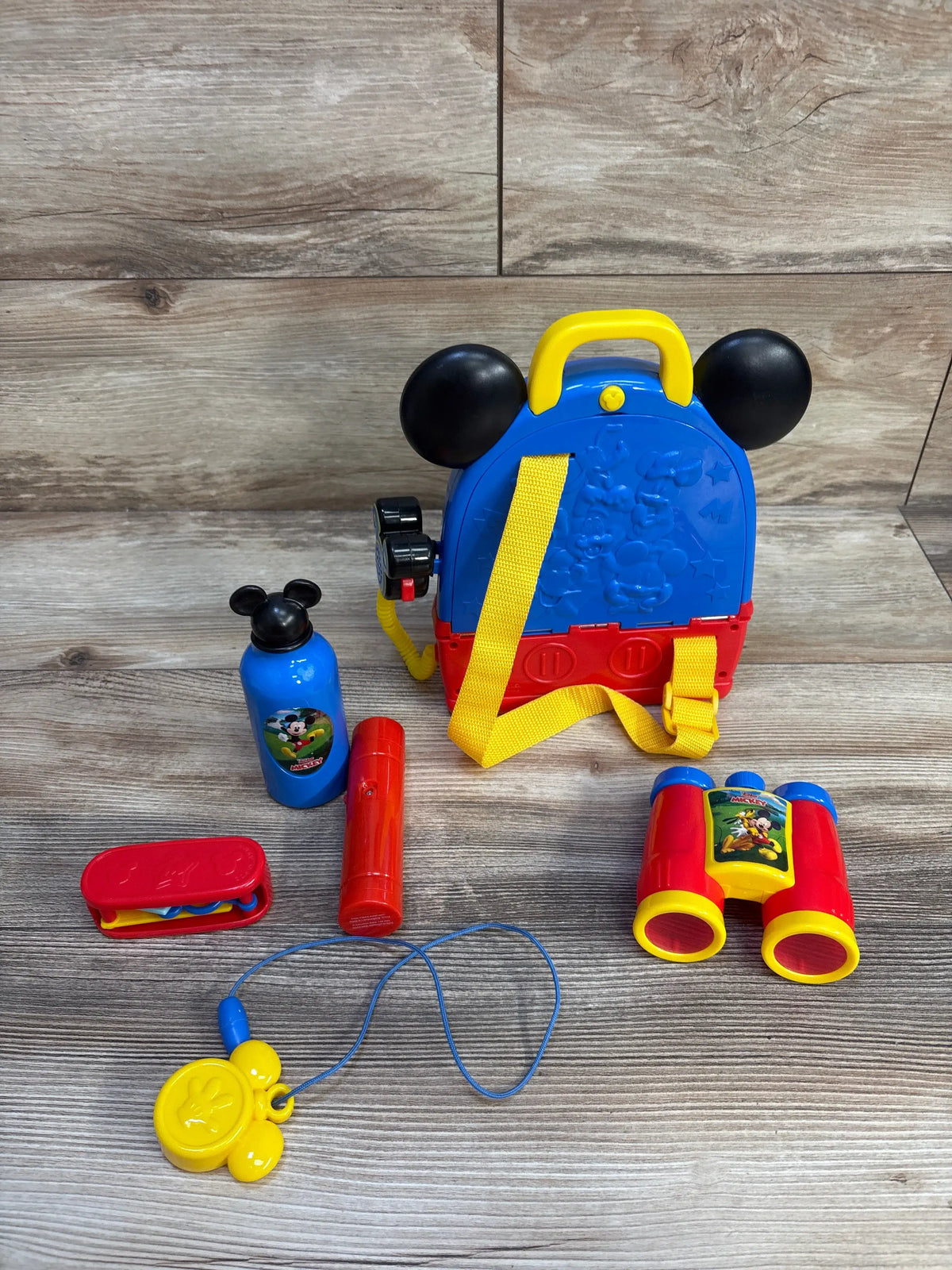 View of Disney Mickey Mouse Funhouse Adventures Backpack Playset with backpack and role play accessories on wood floor