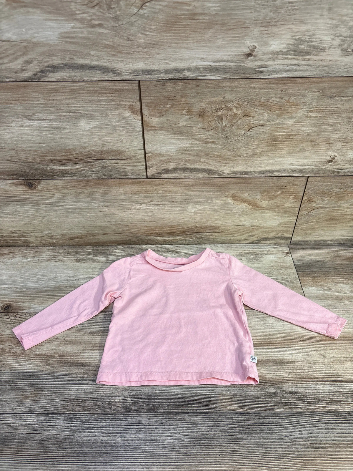 Honest Baby solid pink long sleeve shirt for infants size 12m on a wood background