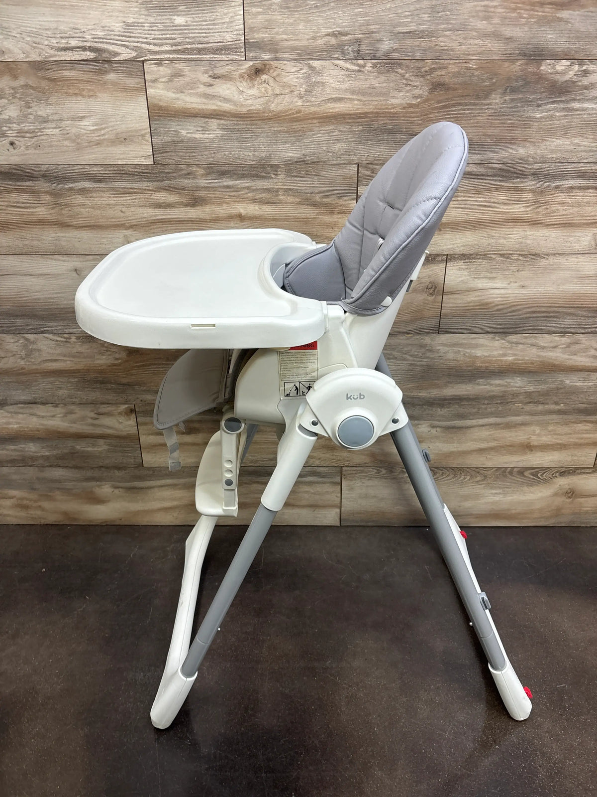 Front view of KÜB 3-in-1 foldable baby high chair in grey showcasing padded seat and tray with wood-look flooring
