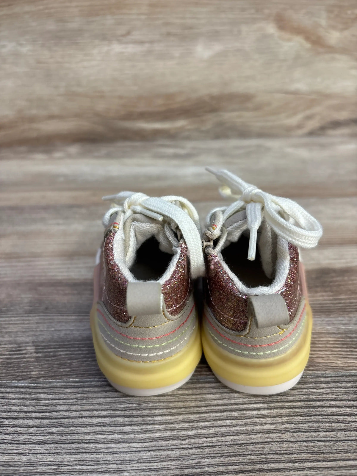 Rear view of Zara pink glittery high top sneakers showcasing pull tabs and white laces on a wood grain surface