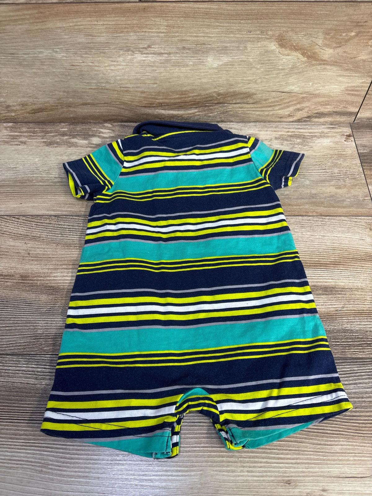 Front view of navy Simple Joys striped polo shortie romper showcasing polo collar and short legs on a wood-grain background