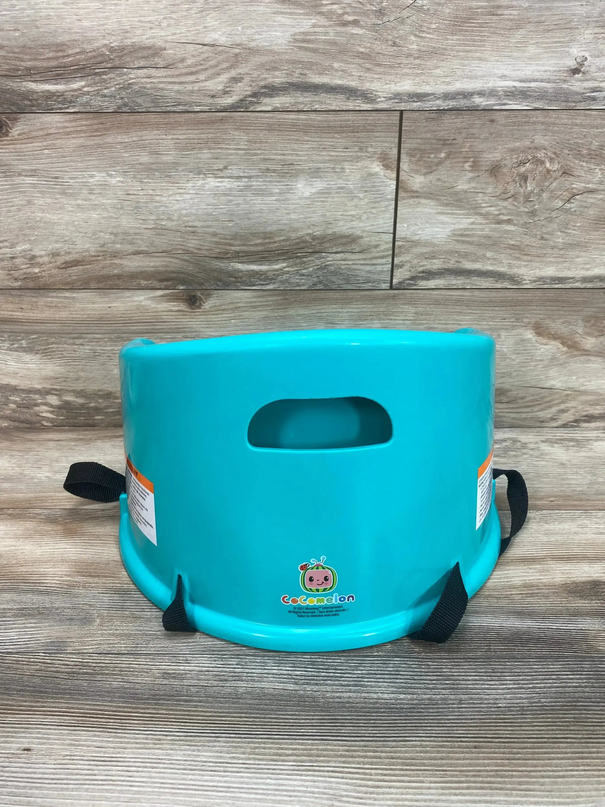 Rear view of Cocomelon 15 inch children’s booster seat showcasing two secure straps and carry handle on wood flooring