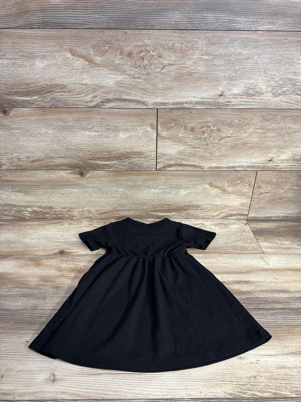 Front view of Shein ribbed baby dress, 18-24m, showcasing short sleeves, gathered waist and ribbed texture on wood-plank floor