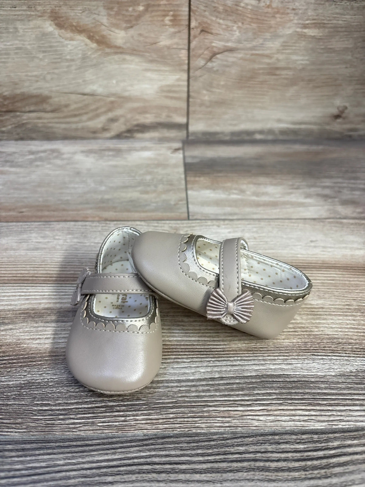 Front and side view of Mayoral Mary Jane shoe in tan showing scalloped trim and bow on strap on wood-look background