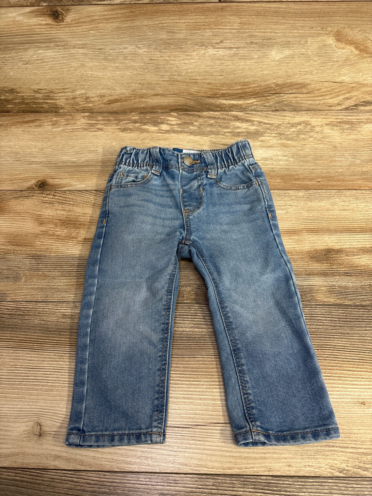 Light blue toddler jeans with elastic waistband on wooden surface, kids clothes resale