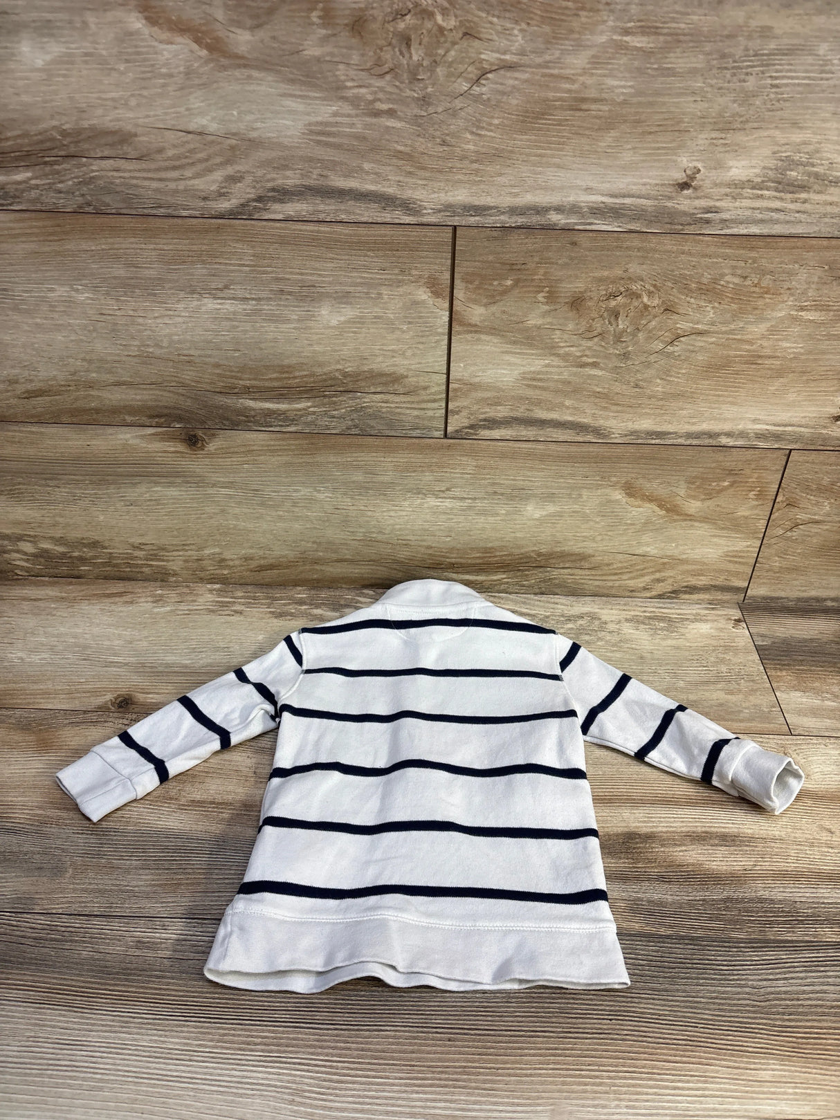 Back of Ralph Lauren baby half-zip sweater with navy stripes and long sleeves on wood floor