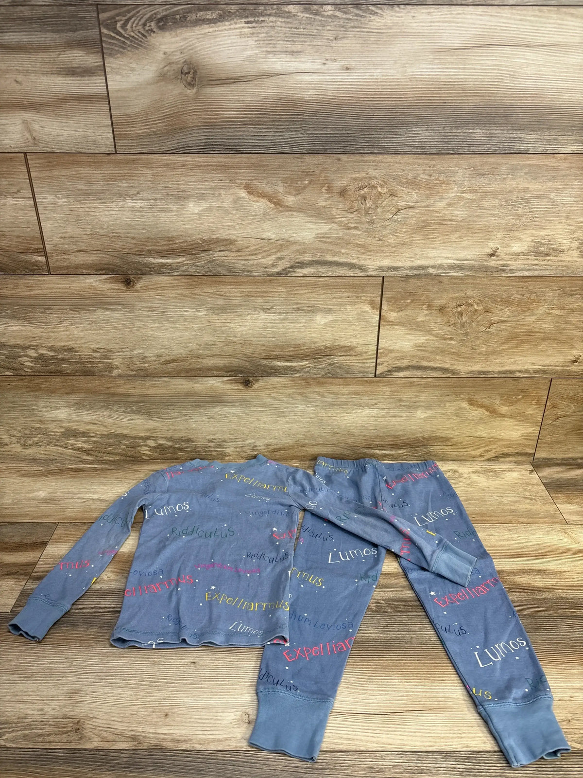 Blue kids pajama set with Harry Potter spell words, long sleeves and pants on wood background