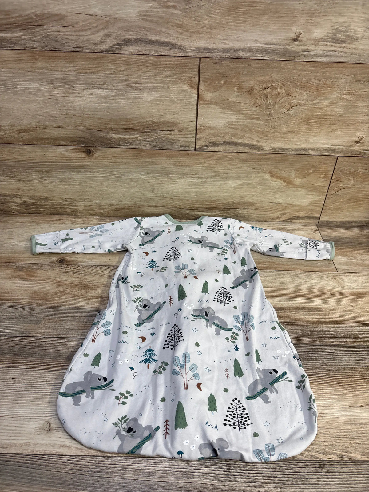 Front view of Jellymoni koala print zip sleep sack showcasing long sleeves and green pattern on a wood-look floor