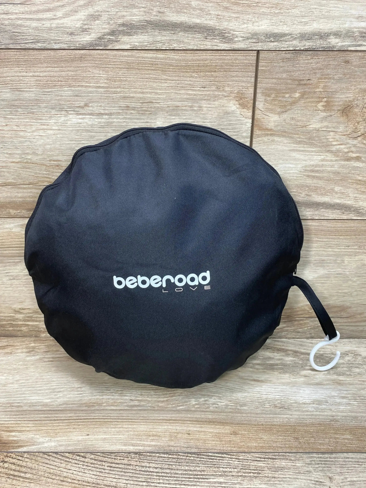Front view of Beberoad Love Crib Tent Mosquito Net in round black carry pouch with white logo and hanging hook on wood