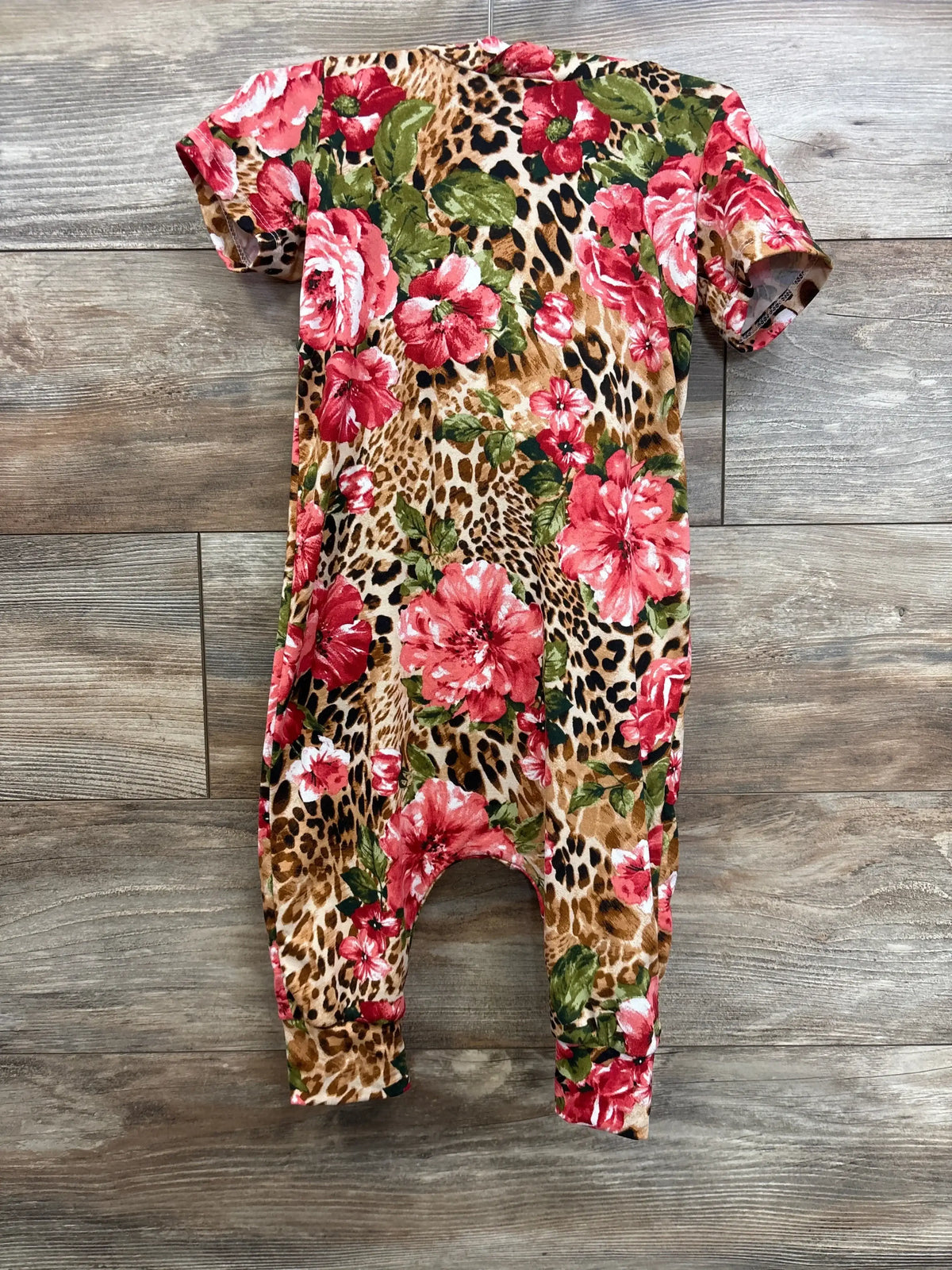 Front view of La Tea Da hooded jumpsuit in red size 3T with floral leopard print and short sleeves on wood