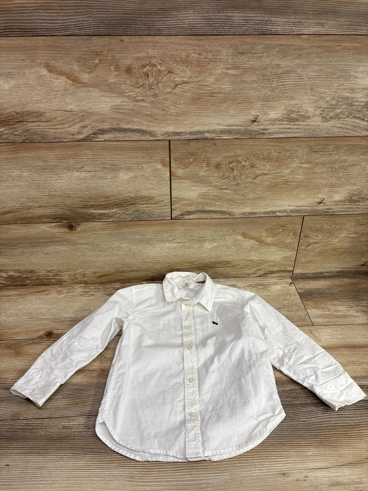 H&M white long sleeve button up shirt for toddlers size 4T on a wood background