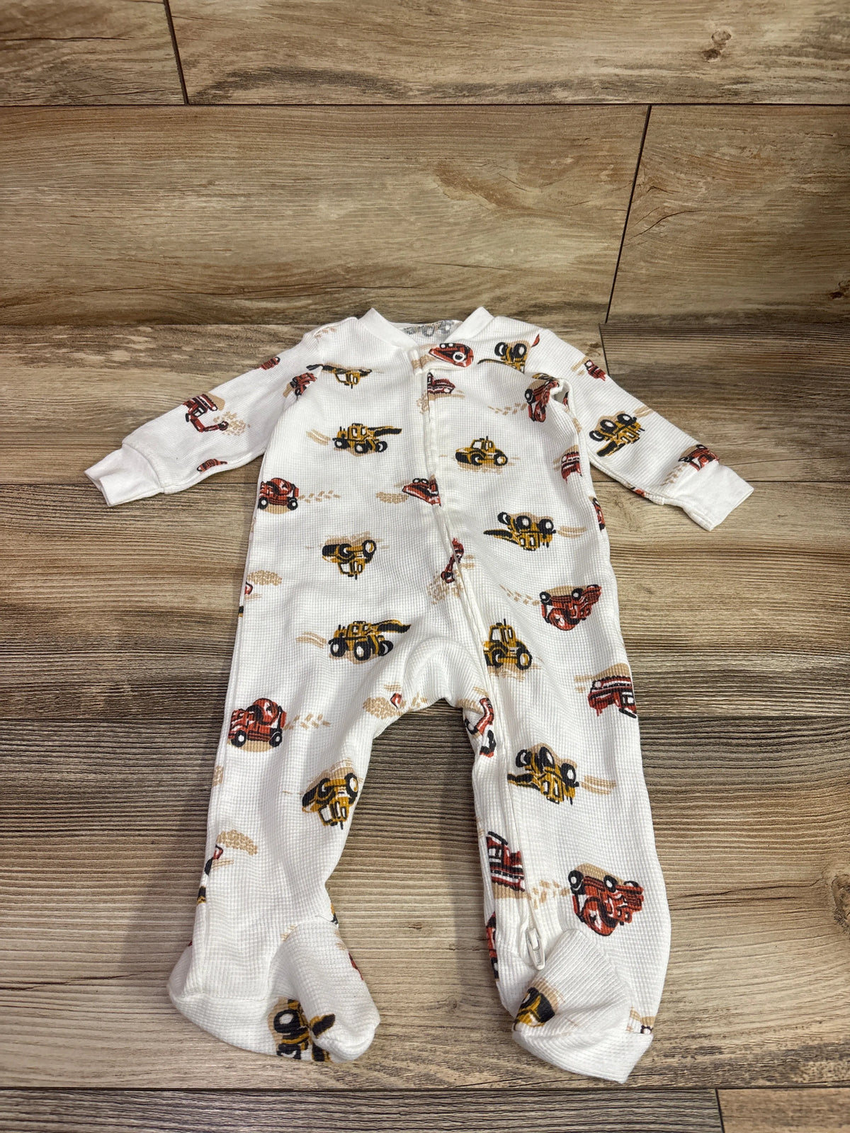Front view of Child of Mine white waffle knit sleeper with footed legs, long sleeves, and construction vehicle print