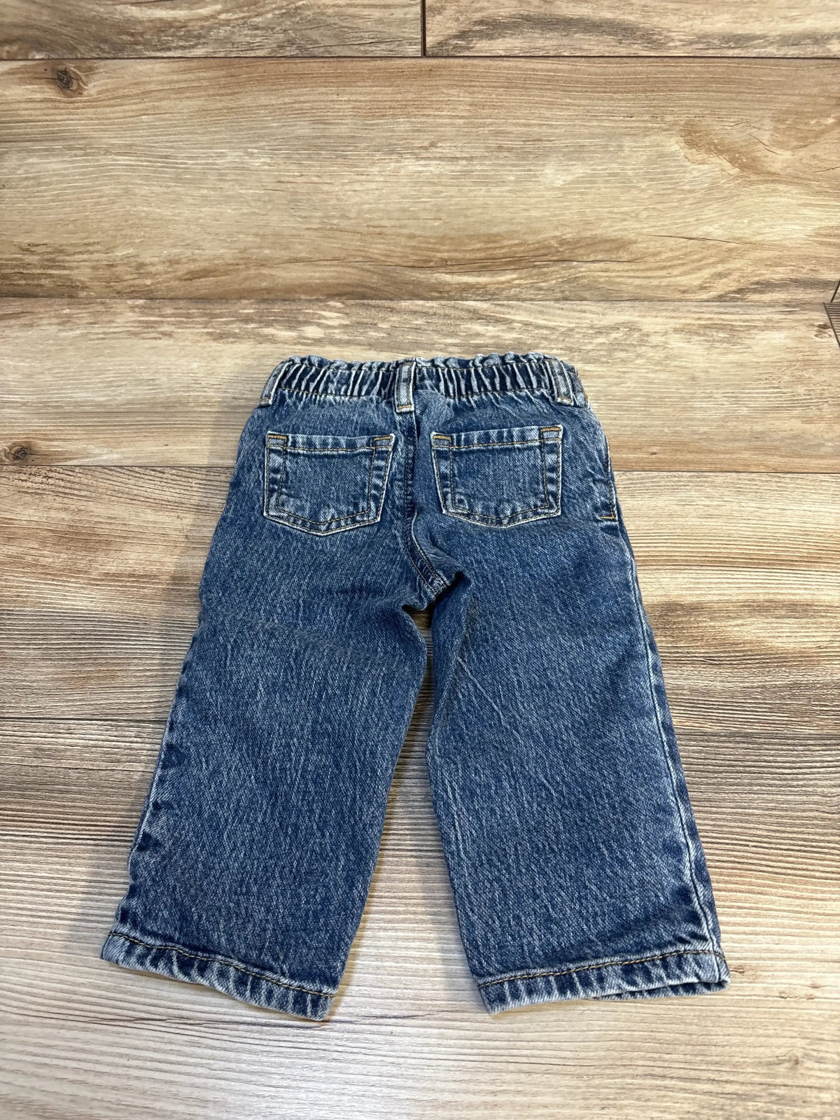 Back view of Cat and Jack paperbag pants, blue, size 18M, elastic waist, back pockets, cuffed hems on wooden floor