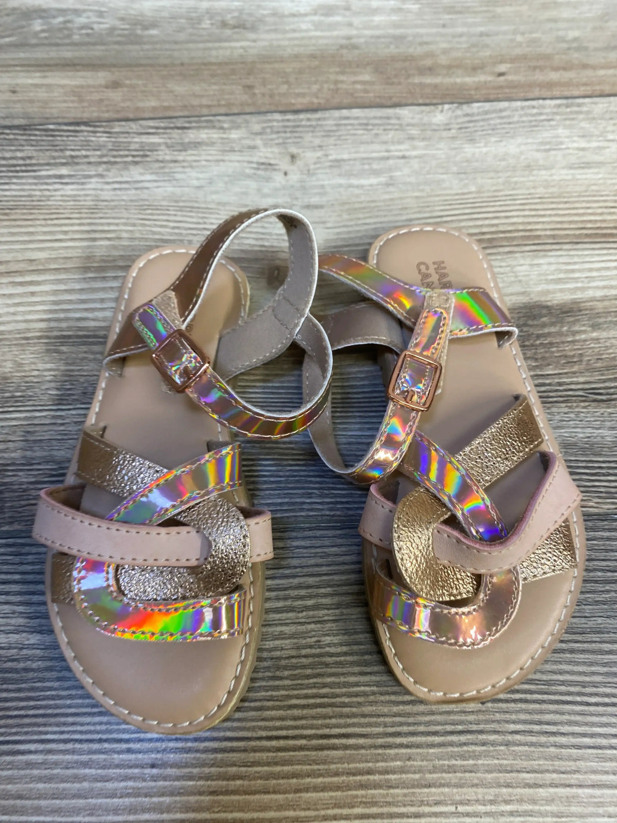 Girls' iridescent strappy sandals with metallic details on wood background