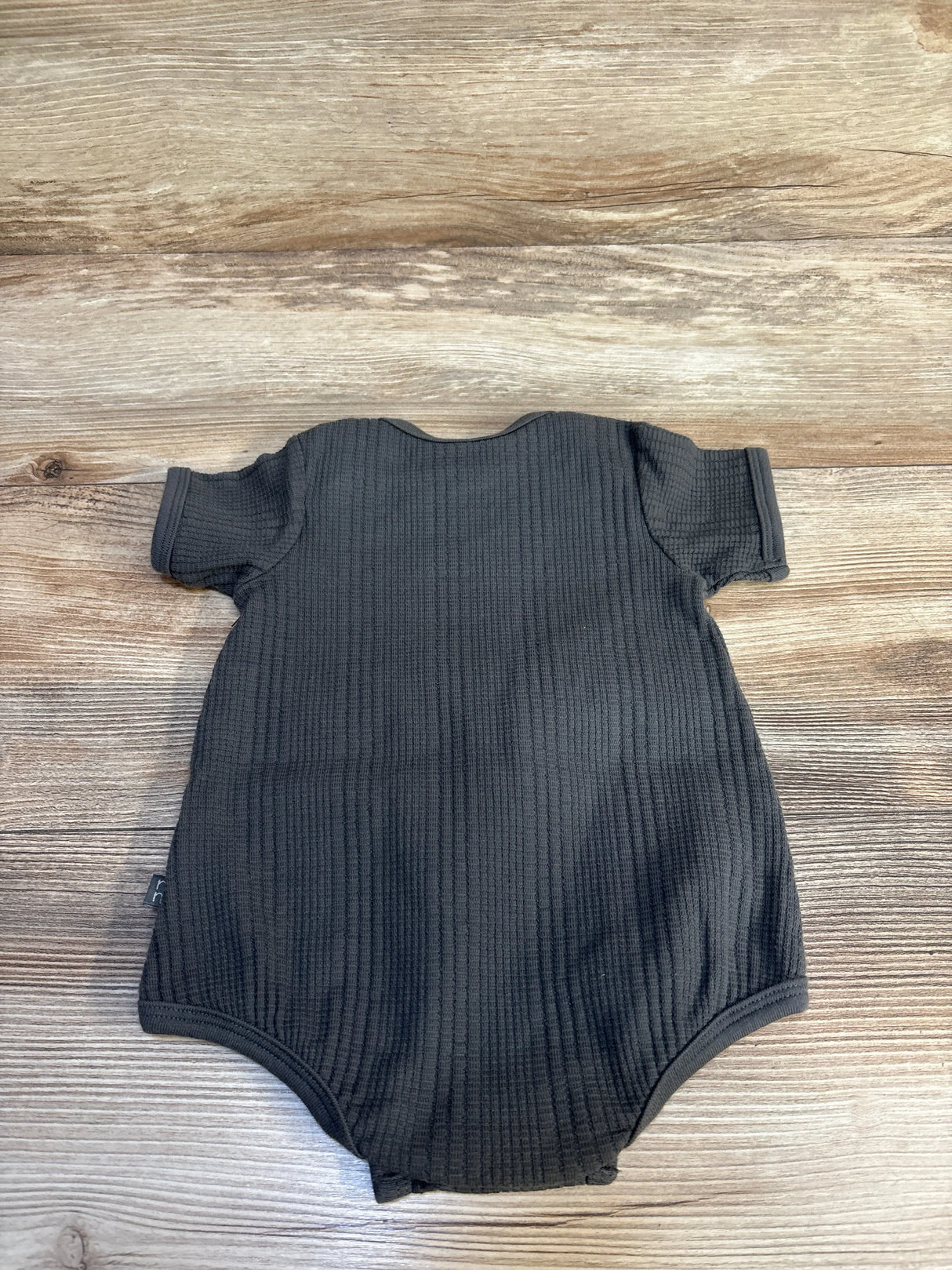 Dark gray ribbed baby onesie with short sleeves on wood floor, ideal for newborns and infants