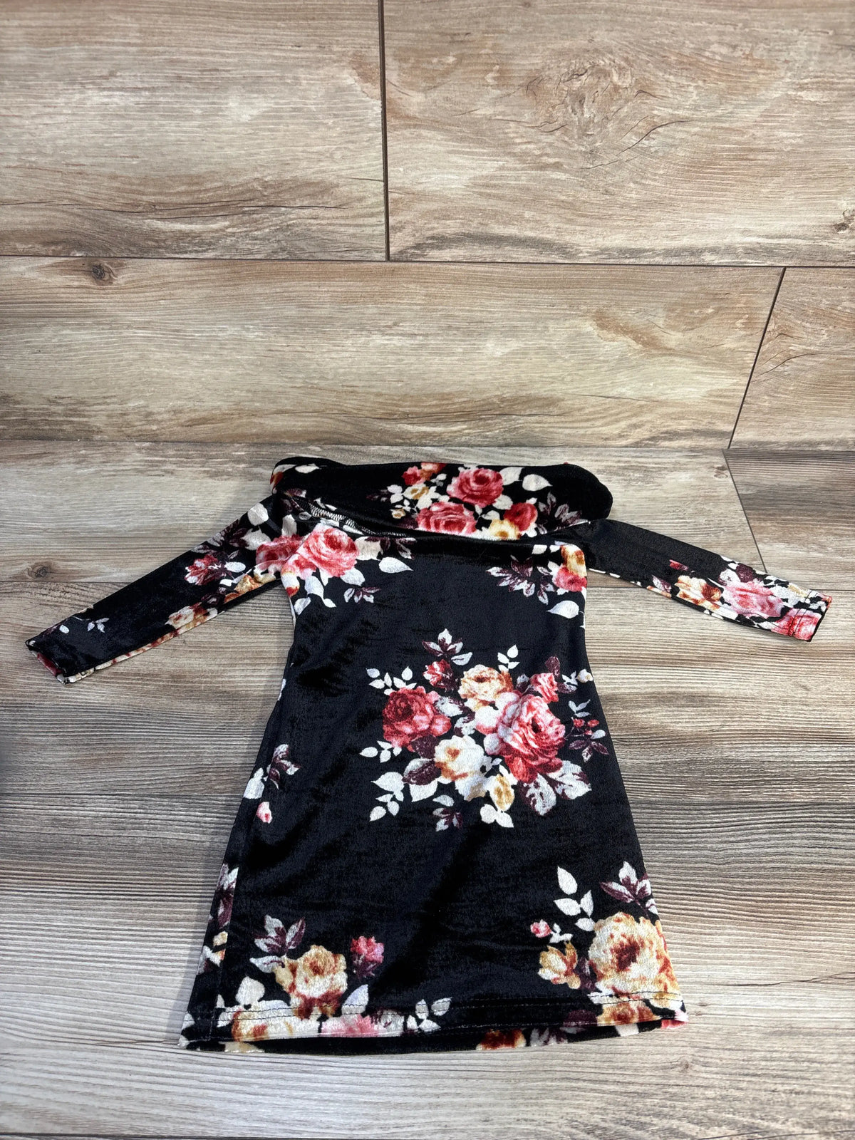 Front view of black Fashion Nova Mini Floral Zone Dress with floral velvet print and off shoulder neckline on wood flooring