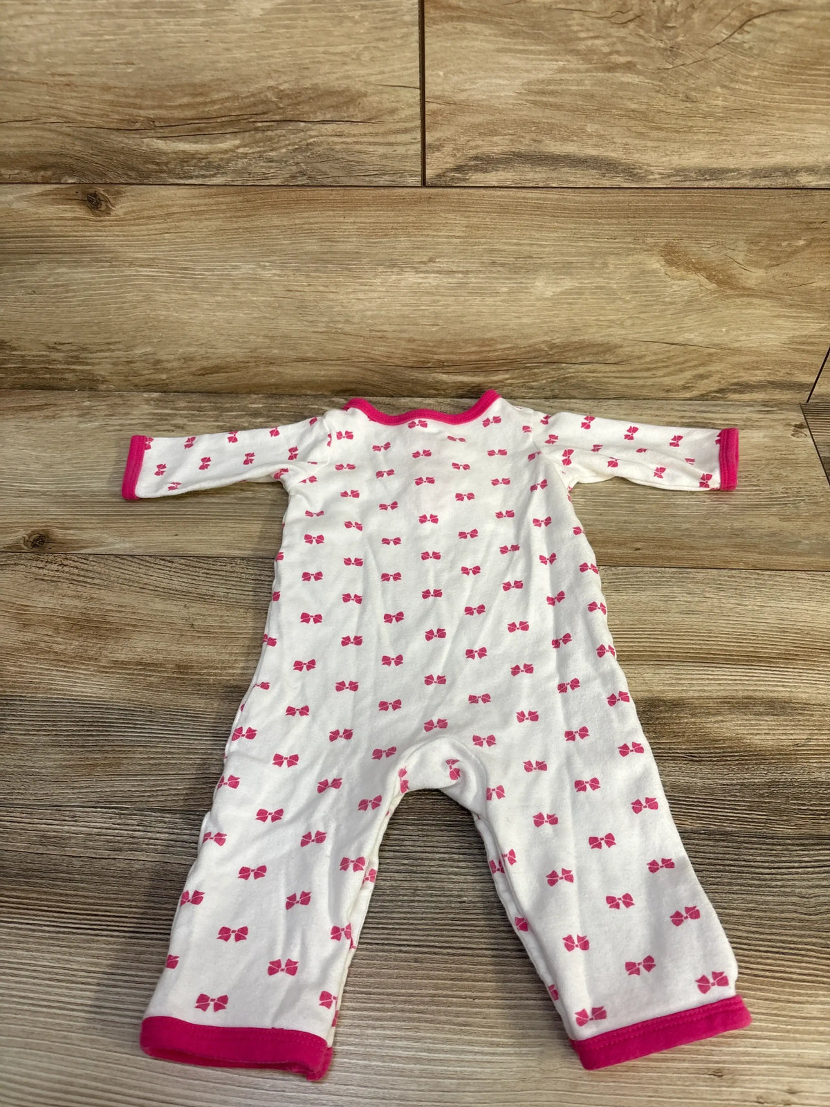 Front view of Hudson Baby white henley bow print coverall showcasing long sleeves and full-length legs on a wood floor