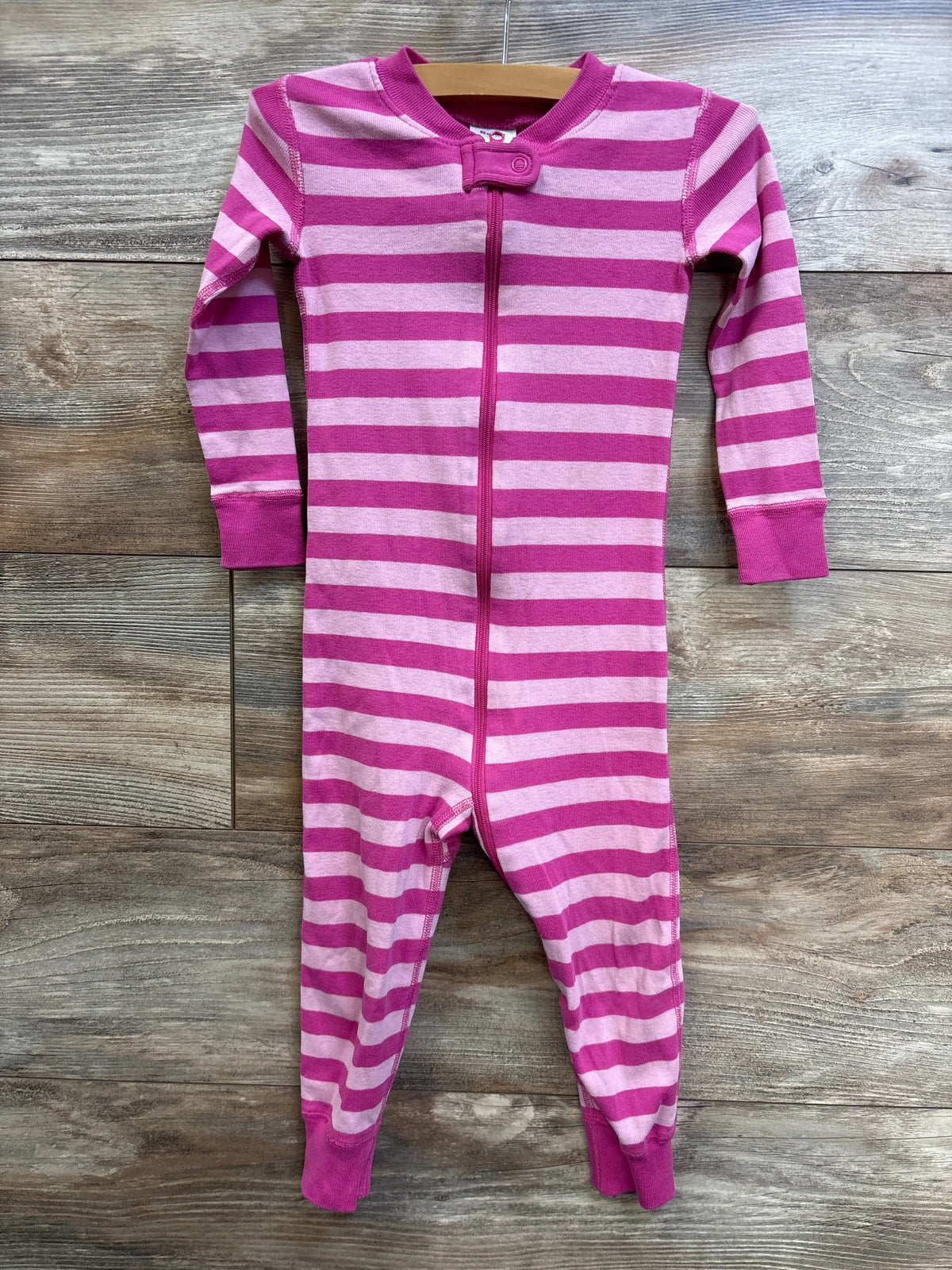 Front view of Hanna Andersson pink striped footless sleeper, size 3T, with front zipper on wood background