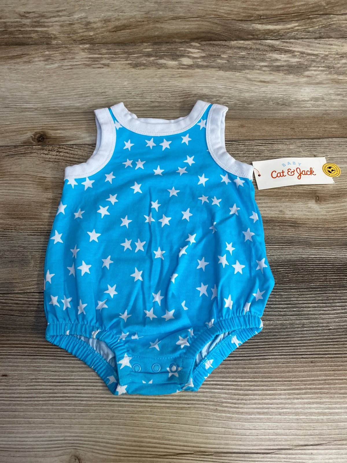 Flat lay of newborn blue Cat and Jack star-print romper showcasing snap crotch closure and white trim on wood background