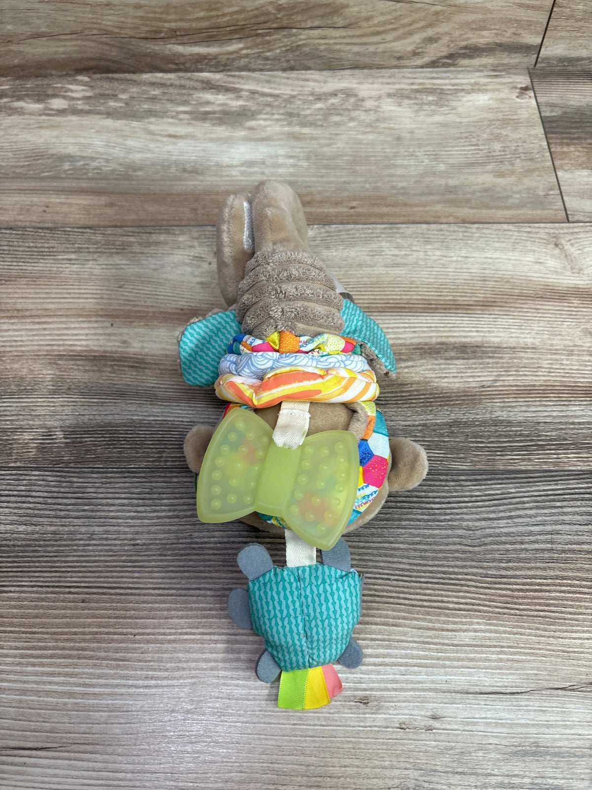 Top view of Infantino Music & Motion Pulldown Monkey showcasing textured fabric and green teether with wood-look floor