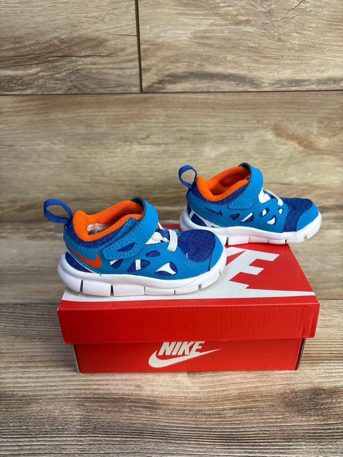 Angled side view of toddler Nike Free Run 2 blue sneakers showcasing mesh upper and flexible sole on white background