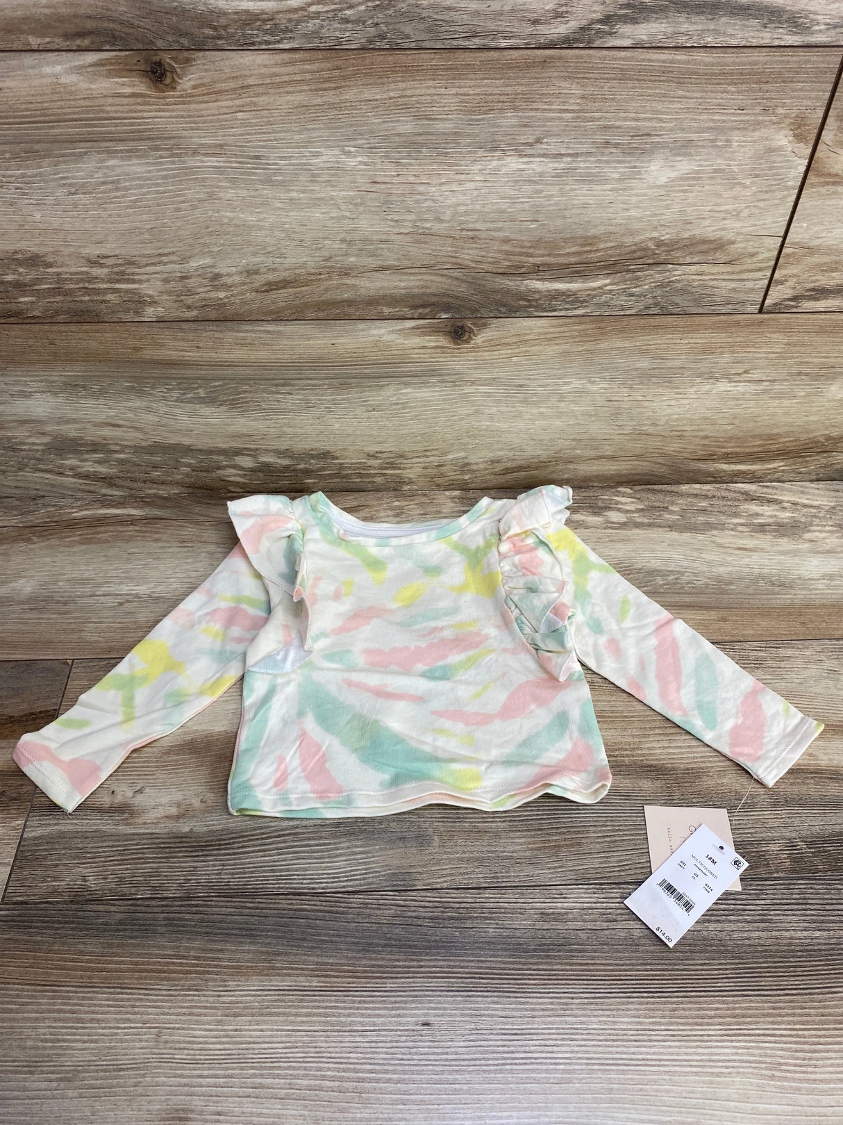 Pastel tie-dye baby long sleeve shirt with ruffle shoulders on wood background