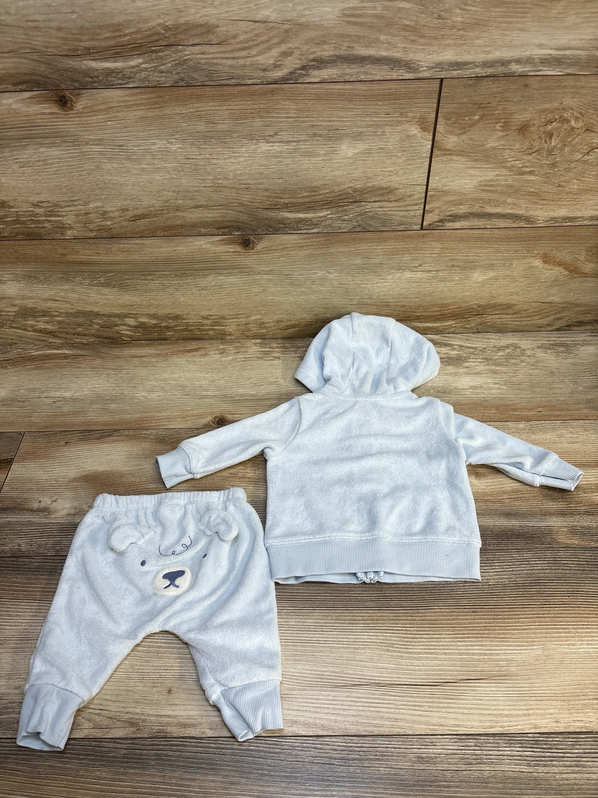 Light gray baby hoodie and bear face pants set on wood background, cozy kids clothing