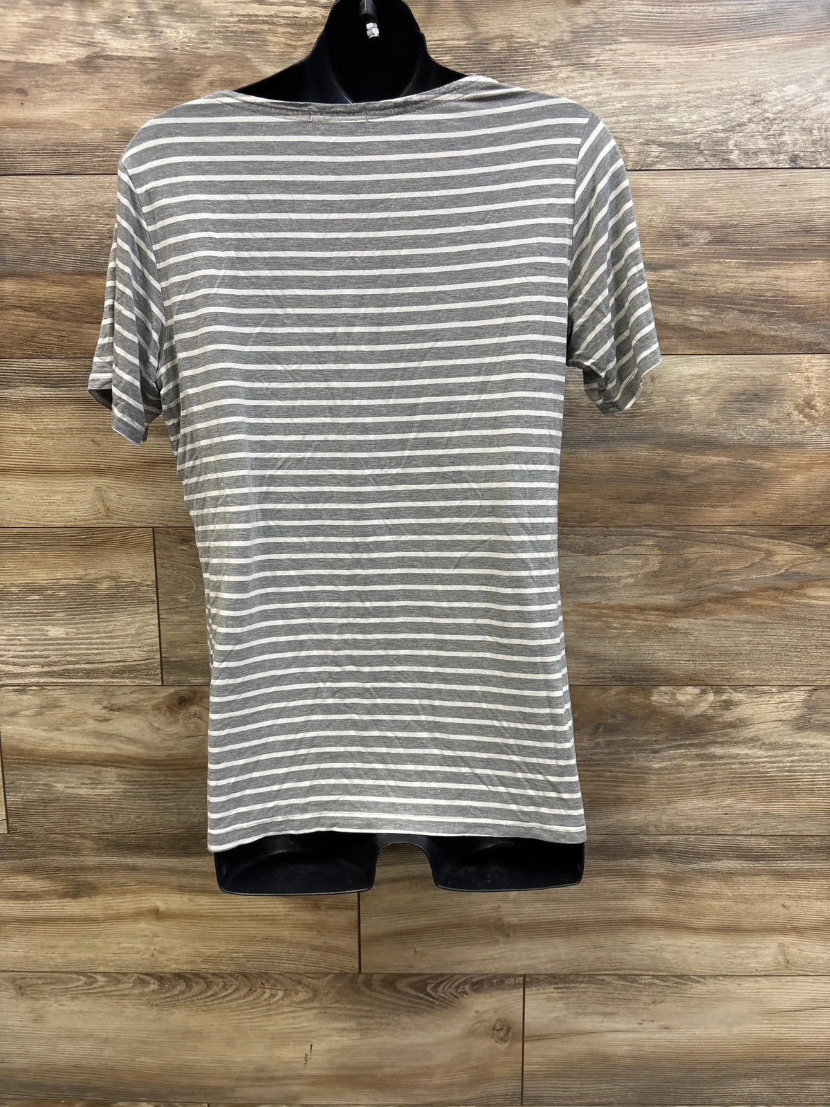 Back view of maternity nursing shirt showcasing grey and white horizontal stripes and short sleeves on a black mannequin against wood background