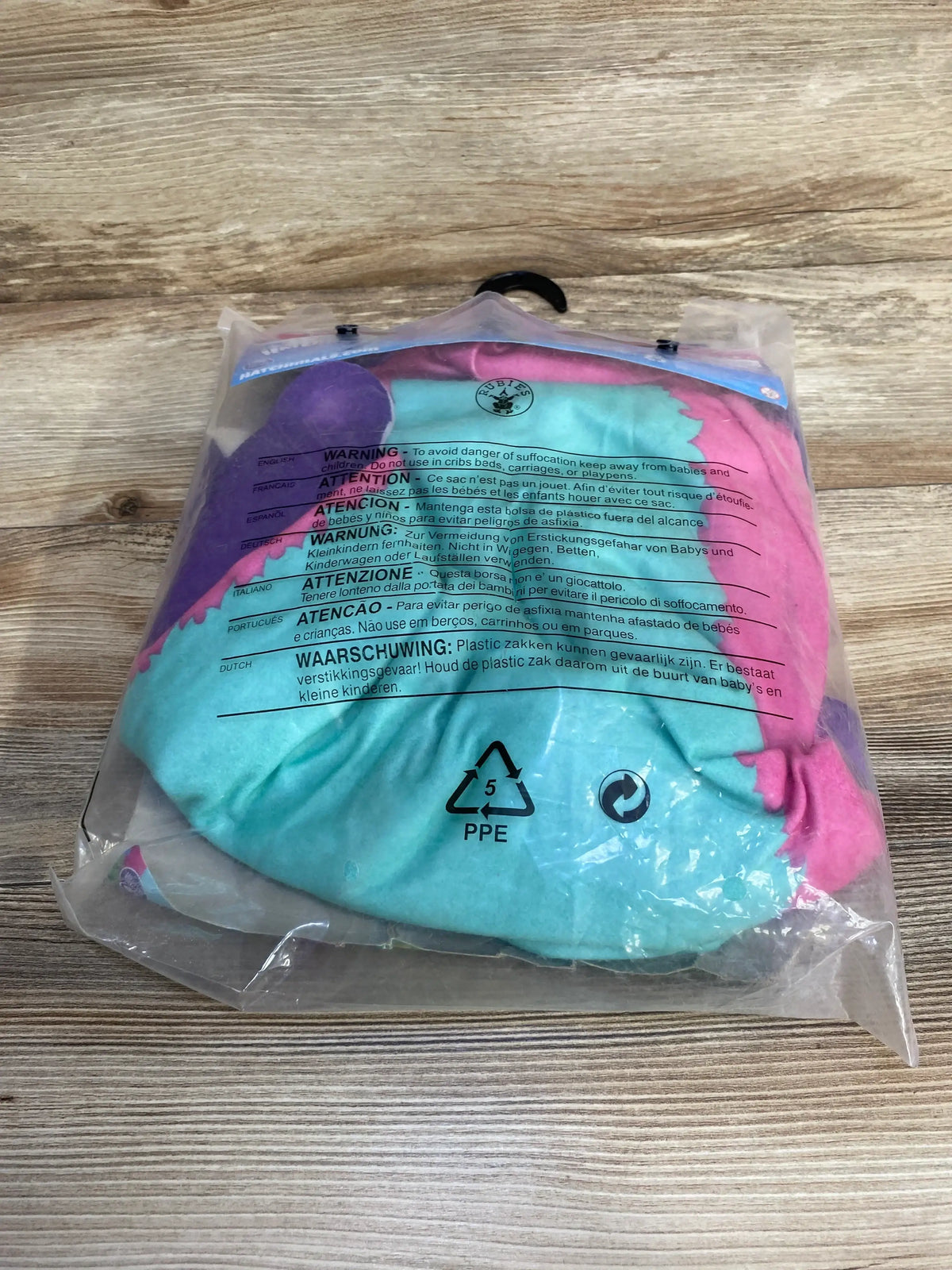 Top view of a pink and turquoise Hatchimals Penguala costume, size 8-10, in clear plastic on a wood-grain surface