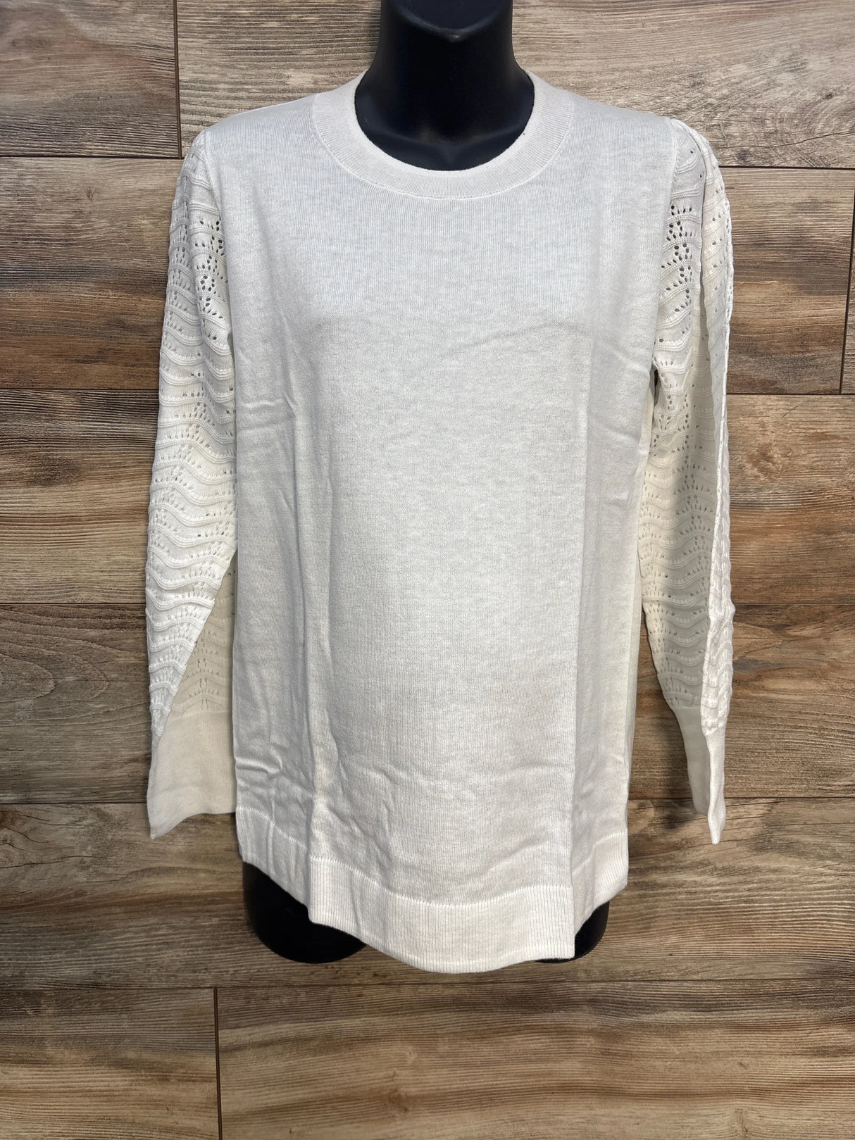 White knit sweater with lace sleeves on mannequin, wood background, women's fashion top