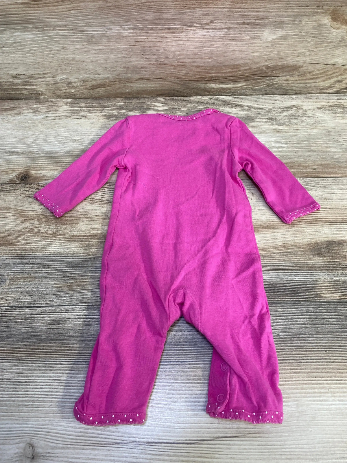 Back view of Carter's pink 3-month coverall showing long sleeves, snap leg closures and white-dot trim on wood background