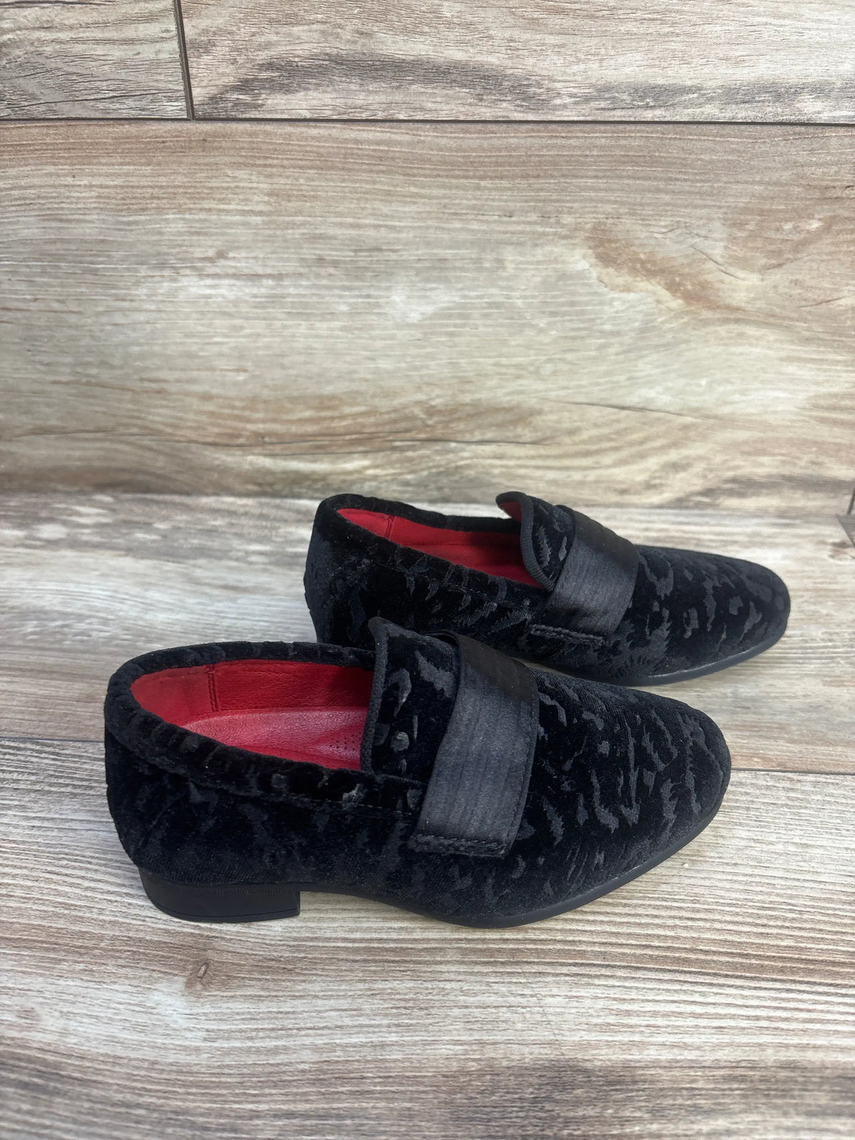 Angled view of Bruno Marc tuxedo dress loafers showcasing black patent PU leather uppers and slip on straps on wood grain