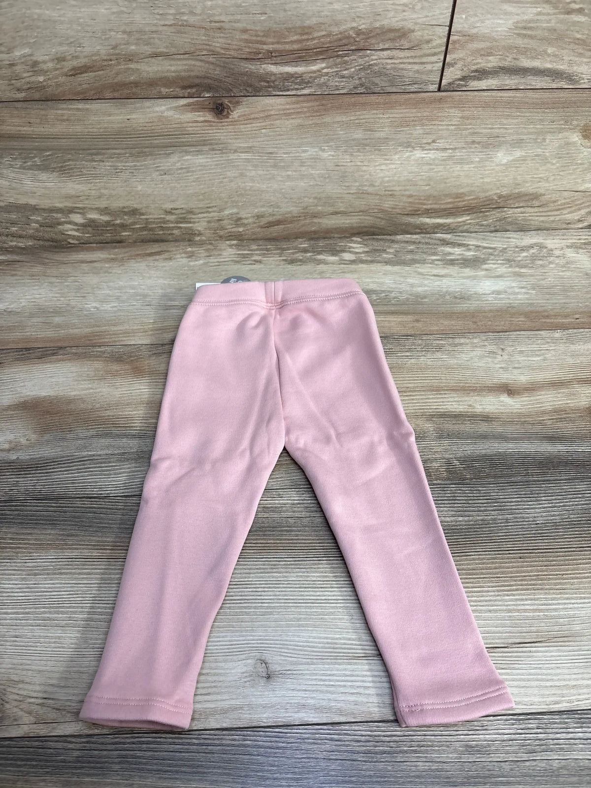Flat lay back view of Baby Gap cozy lined pink leggings, size 18-24 months, showing elastic waistband on wood background