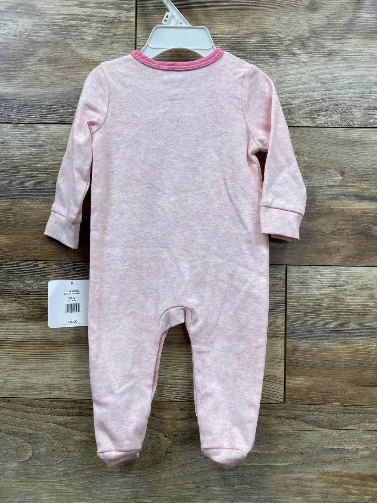 Light pink long sleeve baby sleeper with footies on wooden floor, tag attached