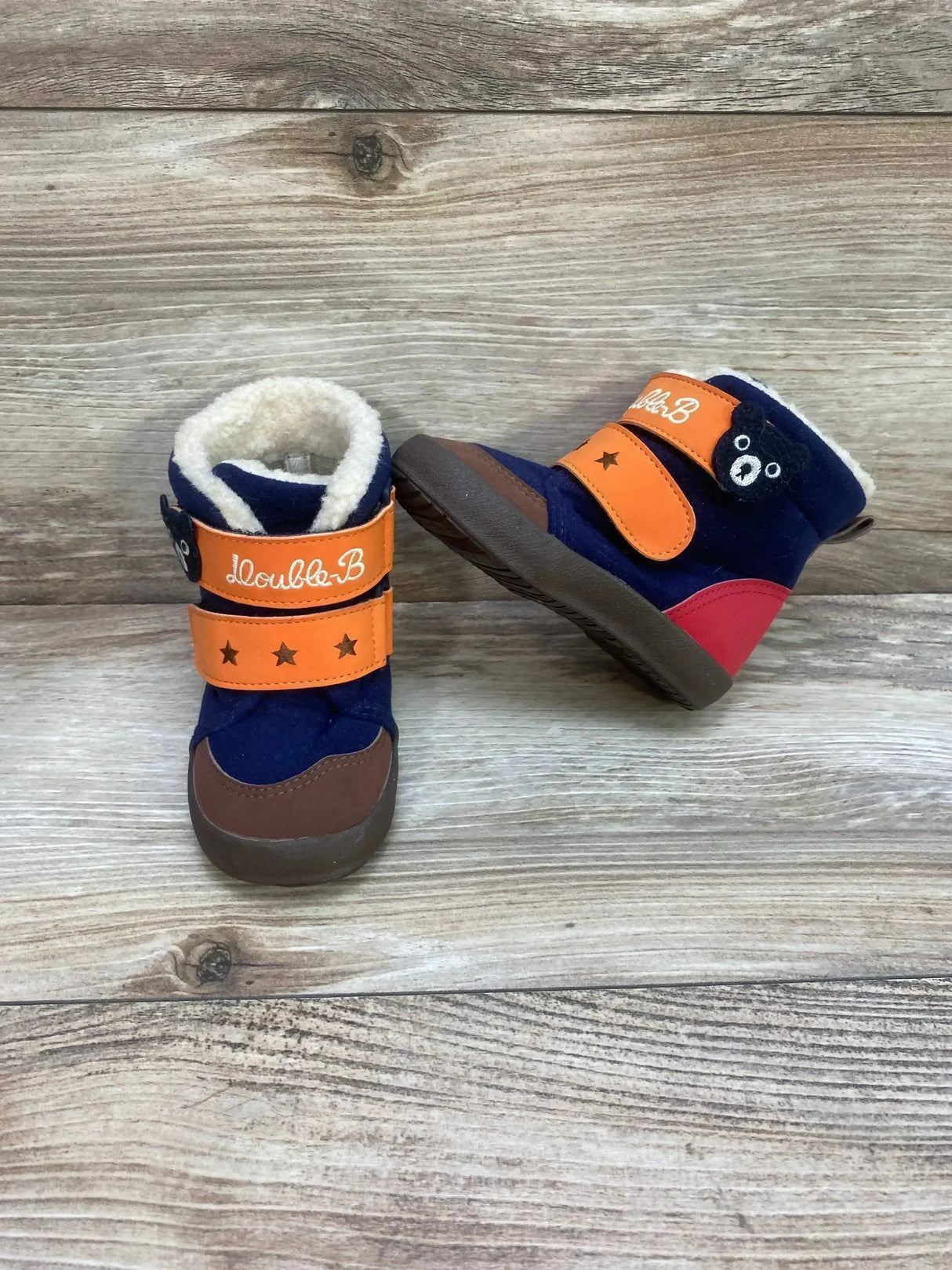 Front and side view of Double B Miki House toddler winter boots, navy with orange straps, stars and bear patch, faux fur lining