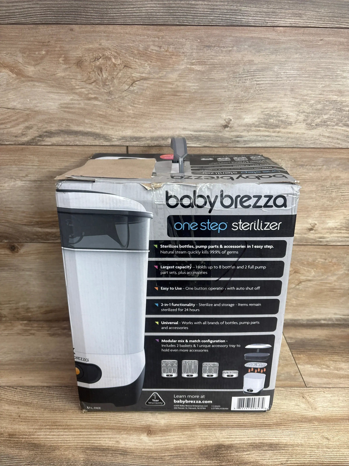 Front of boxed Baby Brezza One Step Sterilizer showcasing product image and features printed on the box with wooden tabletop background