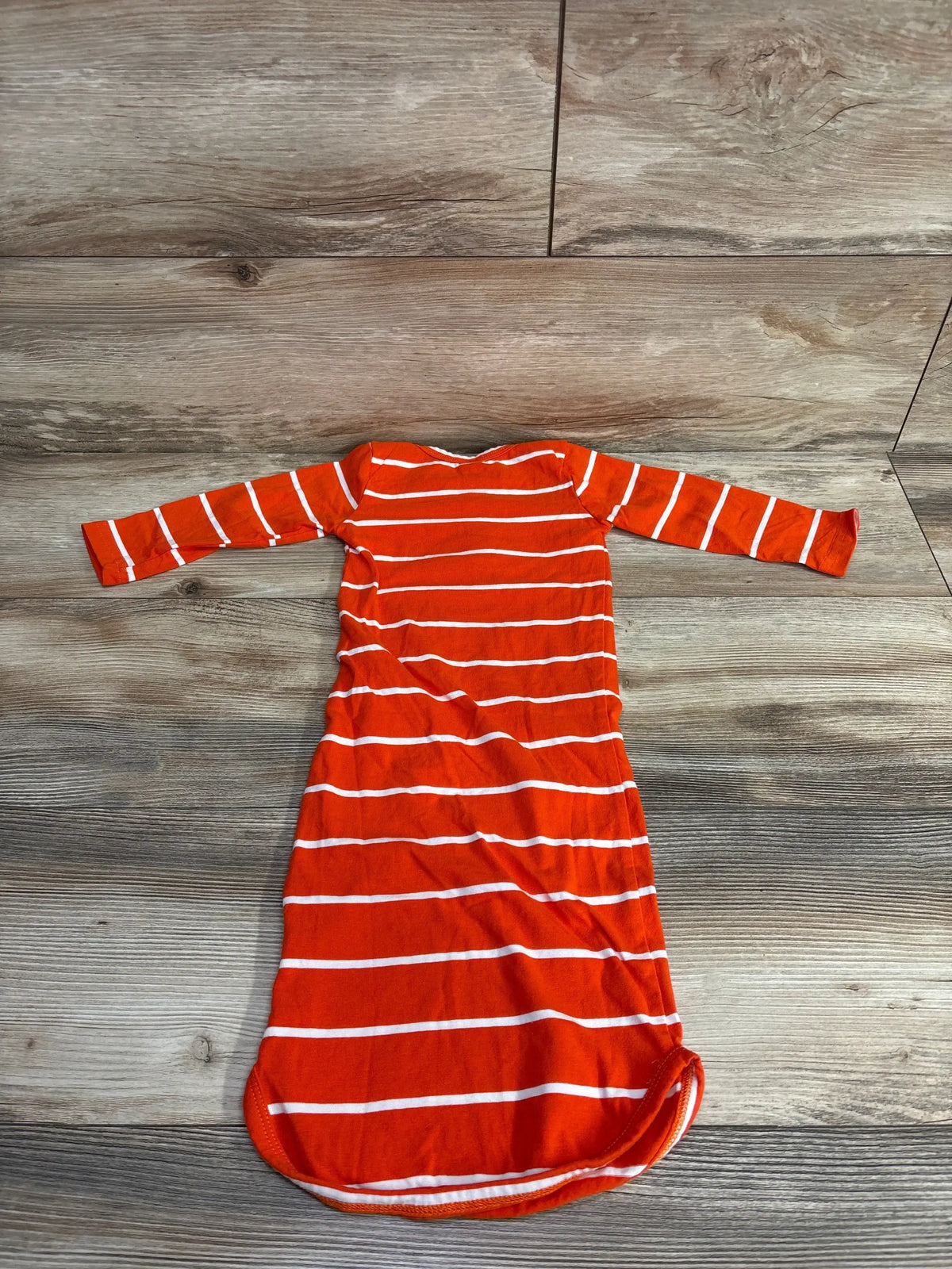 Flat lay of orange and white striped Henley sleeper gown size 3-6M showing long sleeves and gathered bottom on wood floor