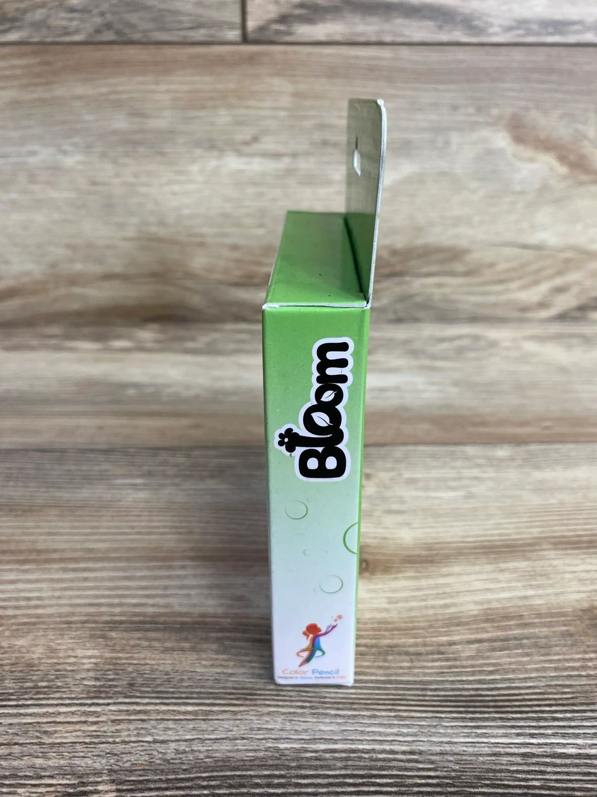 Side view of Color Pencil Flashcards - Bloom 36ct. showcasing green gradient packaging with an open flap on a wooden background