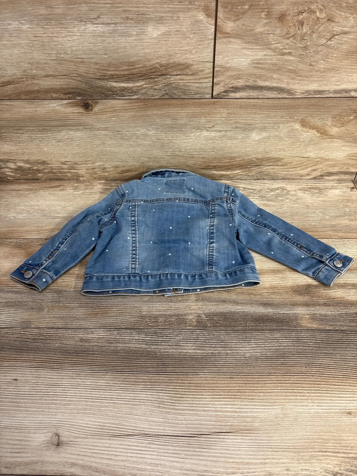 Kids denim jacket with white polka dots laid flat on wooden floor, children's resale clothing